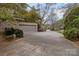 Long driveway leading to a two-car garage surrounded by lush greenery and mature trees at 104 Chalfont Ct, Salisbury, NC 28147