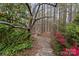 Tranquil backyard garden featuring a stone pathway leading to a rustic metal gazebo surrounded by lush greenery at 104 Chalfont Ct, Salisbury, NC 28147