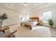 Airy main bedroom featuring natural light, tray ceilings, a wooden accent bed, and an ensuite bathroom at 12526 Dunloe Wood Dr, Huntersville, NC 28078