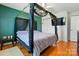 This bedroom features hardwood floors, a ceiling fan, a mounted TV, and a unique four-poster canopy bed with lace and vine accents at 140 Oak Ave, Mount Holly, NC 28120