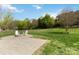 Backyard with stone patio, fire pit, Adirondack chairs, and green lawn at 15118 Marshall Valley Ct, Mint Hill, NC 28227