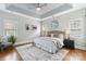 A spacious main bedroom with tray ceilings, hardwood floors, a ceiling fan, and decorative windows at 15118 Marshall Valley Ct, Mint Hill, NC 28227