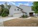 Well-maintained home exterior featuring a two-car garage, stone accents, and landscaped front yard at 15324 Colonial Park Dr, Huntersville, NC 28078