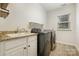 Well-lit laundry room featuring modern washer and dryer, granite counters, and ample cabinet space at 15324 Colonial Park Dr, Huntersville, NC 28078