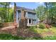 Secluded backyard features a unique stone fireplace, mature trees, and a cozy patio at 1536 Bear Mountain Rd, Charlotte, NC 28214