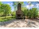 Outdoor stone fireplace and brick patio with mature landscaping offers a great space for entertaining at 1536 Bear Mountain Rd, Charlotte, NC 28214