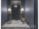 Stylish powder room featuring a marble countertop, modern fixtures, and decorative sconces at 2637 Normandy Rd, Charlotte, NC 28209