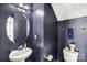 Stylish powder room featuring dark walls, a pedestal sink, decorative mirror, and modern fixtures at 3010 Berry Creek Rd, Charlotte, NC 28214