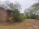 View of the side and backyard of a single story brick home on a wooded lot at 307 Brook St, Salisbury, NC 28146