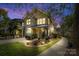 Charming two-story townhome featuring well-lit exterior, landscaped yard, and inviting front porch at twilight at 3414 Chagall Ct, Charlotte, NC 28205