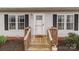 Close-up of the home's entrance with a charming wooden porch, decorative accents, and stylish exterior lighting at 34958 Lowder Rd, New London, NC 28127
