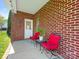 Charming covered patio area with red chairs and brick siding at 4303 Patriots Hill Rd, Mint Hill, NC 28227