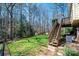 Backyard featuring a grassy lawn, mature trees, and a wooden staircase leading to an upper level deck at 5451 Gunpowder Dr, Hickory, NC 28601