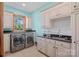 Bright laundry room with modern washer/dryer, tiled floor, and ample cabinet space at 5546/5510 Hoodtown Rd, Sharon, SC 29742