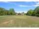 Expansive green yard with mature trees, fire pit, and a charming home in the background at 5546/5510 Hoodtown Rd, Sharon, SC 29742