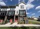 Modern two-story townhome featuring brick accents, a small balcony, an orange front door, and manicured lawn at 648 W End Dr, Charlotte, NC 28208