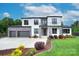 Stunning two-story modern home with stone accents, black framed windows, landscaped yard, and three-car garage at 7005 W Duncan Rd, Indian Trail, NC 28079