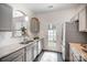 Galley kitchen with stone countertops, stainless appliances, gray cabinets and a door to the outside at 7445 Abigail Glen Dr, Charlotte, NC 28212