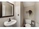 Half-bathroom featuring a modern pedestal sink, a decorative mirror, and a toilet with charming wall decor at 9052 Meadowmont View Dr, Charlotte, NC 28269