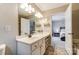 Bathroom vanity with a large mirror, white cabinets, drawers, and view into an adjacent bedroom at 9052 Meadowmont View Dr, Charlotte, NC 28269