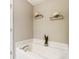 Bright white bathtub with modern fixtures and decorative floating shelves for plants and flowers at 9052 Meadowmont View Dr, Charlotte, NC 28269