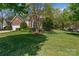 Well-maintained lawn with mature tree, and lovely landscaping surrounding a charming brick home at 11841 Mourning Dove Ln, Charlotte, NC 28269