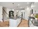Open kitchen with white cabinets, a dark island with seating, stainless appliances and hardwood floors, and staircase on the left at 13752 Roderick Dr # 175, Huntersville, NC 28078