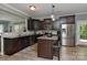 Updated kitchen with dark cabinets, granite counters, stainless appliances, island with seating and wood-look floors at 15035 Ockeechobee Ct, Mint Hill, NC 28227
