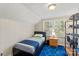 This cozy bedroom features wood-paneled walls, a striking blue rug, and a bright window for natural light at 206 23Rd Nw St, Hickory, NC 28601