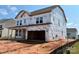 New construction with Tyvek wrap features a two-car garage and covered porch under a blue sky at 2212 Indigo Branch Rd, Indian Land, SC 29707