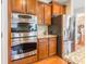 Modern kitchen featuring stainless steel double oven, refrigerator, granite countertops, and wooden cabinets at 2610 Mchanna Pt, Fort Mill, SC 29708