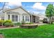 A bright daytime shot of the back of the home with a screened in porch, stone patio and manicured landscaping at 331 Miners Cove Way, Fort Mill, SC 29708