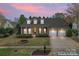 Charming brick home featuring a manicured lawn, dormer windows, and an attached two-car garage at sunset at 331 Miners Cove Way, Fort Mill, SC 29708