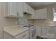 Kitchen area with white cabinets, laminate countertops, range, and wood-look flooring at 3835 Mohawk Ct, Charlotte, NC 28215