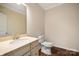 Bathroom featuring marble vanity, toilet, hardwood flooring, and stylish wallpaper at 4006 Fall Oak Ter, Fort Mill, SC 29707