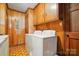 Functional laundry room with wood paneled walls and built-in cabinets above white washer and dryer at 422 Sherrill Farm Rd, Lincolnton, NC 28092
