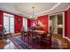 Formal dining room with red walls, chandelier, and view into the butler's pantry at 615 Reliance Ct, Tega Cay, SC 29708