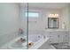 Bright bathroom featuring a soaking tub with a tiled surround, glass shower and a vanity with an undermount sink at 8313 Balcony Bridge Rd, Huntersville, NC 28078