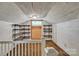 Attic with white wood paneling, small window, carpeted floor and custom built in shelving at 8974, 8972 & 8970 Nc 90 E Hwy, Stony Point, NC 28678