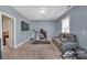This bonus room features a plush gray sofa, treadmill, TV, and carpeting at 9032 Cornflower Dr, Harrisburg, NC 28075