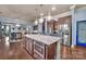 Kitchen island with stainless steel microwave and refrigerator, modern light fixtures, and view to dining area at 9032 Cornflower Dr, Harrisburg, NC 28075