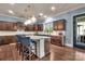Kitchen featuring dark brown cabinets, a large island with barstool seating, and modern lighting fixtures at 9032 Cornflower Dr, Harrisburg, NC 28075