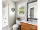 Well-lit bathroom with a wooden vanity, decorative mirror, and shower-tub combination with neutral decor at 10609 Washam Potts Rd, Cornelius, NC 28031