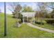 Outdoor picnic and grill area with a covered pergola, table, benches and mature trees at 10720 Hill Point Ct, Charlotte, NC 28262