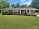 Charming single-story brick home featuring a well-manicured lawn and a cozy, white-railed front porch at 1121 Rembrandt Sw Dr, Concord, NC 28027