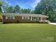 Charming single-story brick home featuring a well-manicured lawn and a cozy, white-railed front porch at 1121 Rembrandt Sw Dr, Concord, NC 28027