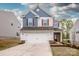 Charming two-story home with a white garage, blue shingle siding, and red shutters on the front windows at 123 Abersham Dr, Mooresville, NC 28115