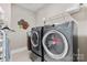 Well-lit laundry room featuring side-by-side washer and dryer and storage shelving with an eclectic flower wall decoration at 1320 Huntcliff Dr, Waxhaw, NC 28173