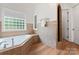 Bathroom with a soaking tub, tiled walls, hardwood floors, and a tiled shower surround at 1328 Astoria Pkwy, Catawba, NC 28609