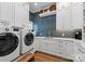 Well-lit laundry room featuring front-loading washer and dryer, white cabinetry, and unique blue backsplash at 1328 Astoria Pkwy, Catawba, NC 28609